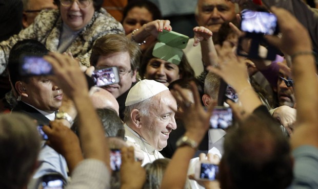 n FILE – In this July 11, 2015 file photo, Pope Francis is surrounded by people taking pictur...