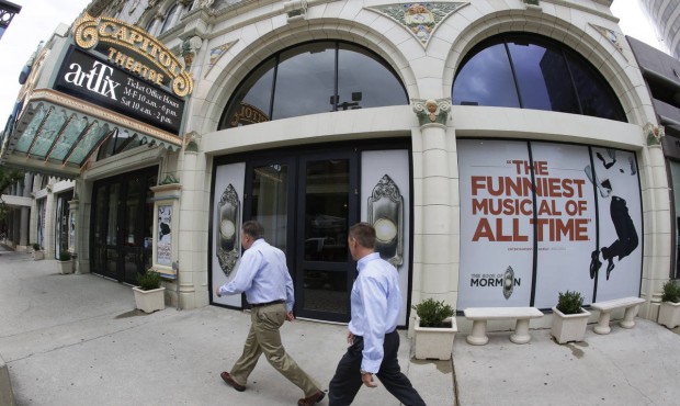 People walk past signs announcing the “Book of Mormon” musical at the Capitol Theatre, ...